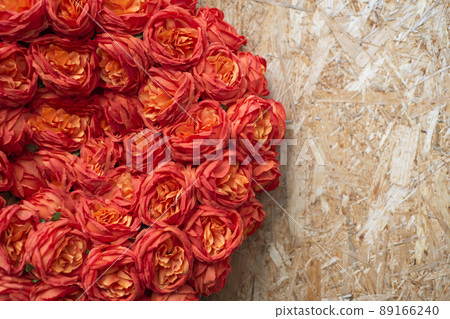 Artificial flowers texture on plywood with copy space. Orange roses, floral background 89166240