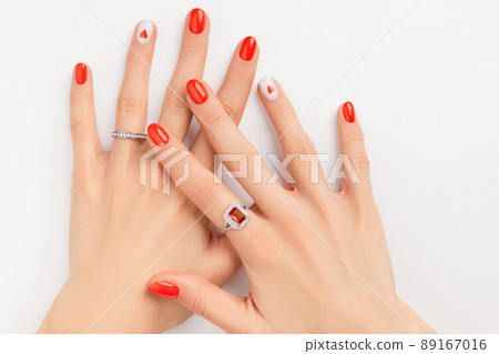 Womans hands with fashionable red manicure on white background. Summer nail design with heart Womans hands with fashionable red manicure on white background. Summer nail design with heart 89167016