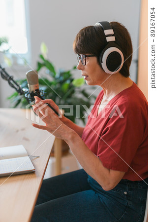 Middle-aged woman radio host making podcast recording for online show - broadcast and dj concept Middle-aged woman radio host making podcast recording for online show - broadcast and dj concept 89167054