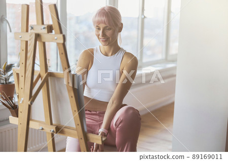 Attractive positive lady artist at work upon new picture at home 89169011