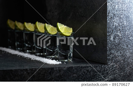 Tequila with lime and sea salt on a black table. Tequila with lime and sea salt on a black table. 89170627