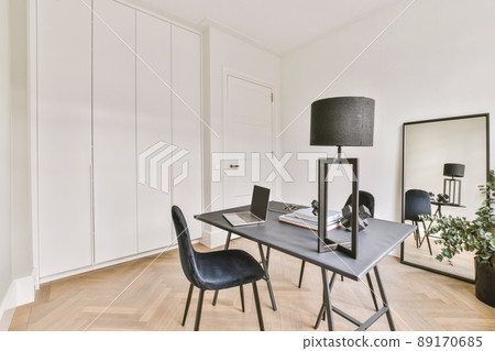 A workplace with a laptop on a table in a spacious, bright room A workplace with a laptop on a table in a spacious, bright room 89170685