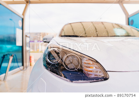 water droplets on the headlight of a white car. self-service car wash. car washer. water droplets on the headlight of a white car. self-service car wash. car washer. 89170754
