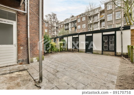 A small courtyard with a tiled floor and a high fence with a door in it 89170758