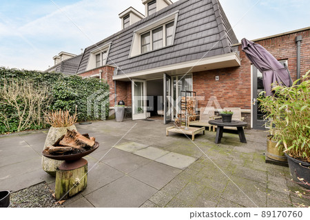 A spacious courtyard behind a residential building with a separate seating area on a tiled floor A spacious courtyard behind a residential building with a separate seating area on a tiled floor 89170760