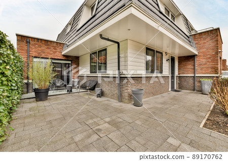 Entrance to a small private house with a tiled roof, a fence made of bushes and a tiled road Entrance to a small private house with a tiled roof, a fence made of bushes and a tiled road 89170762