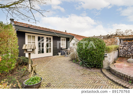 A backyard with brick paths, plants and a small sitting area near a private cozy house A backyard with brick paths, plants and a small sitting area near a private cozy house 89170768
