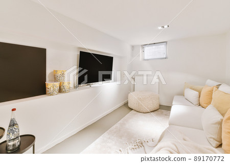 A guest area with a large white sofa in front of a large TV in a modern house A guest area with a large white sofa in front of a large TV in a modern house 89170772