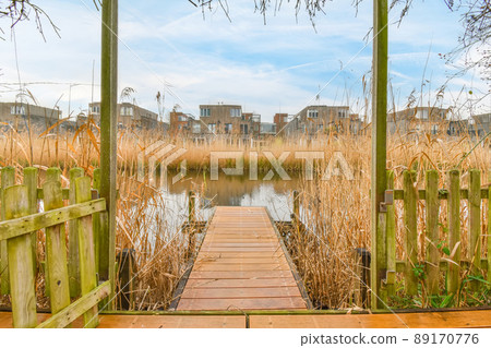 A small wooden pier leading to a river overgrown on both banks 89170776