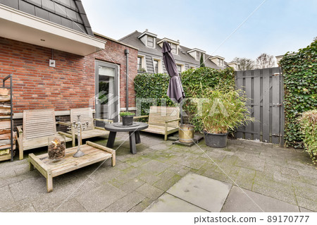 A spacious courtyard behind a residential building with a separate seating area on a tiled floor 89170777