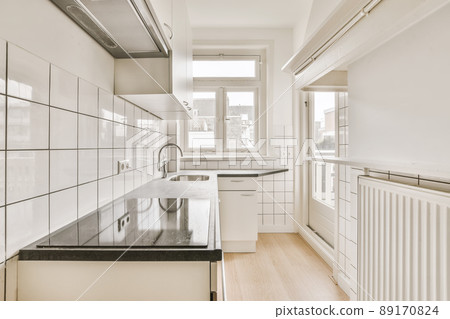 Cozy bright kitchen with a black countertop and a white kitchen set Cozy bright kitchen with a black countertop and a white kitchen set 89170824