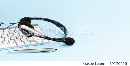 Headset over keyboard on blue background Headset over keyboard on blue background 89170916