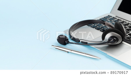 Headset over laptop on blue background Headset over laptop on blue background 89170917