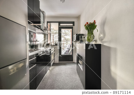 Kitchen in dark colors with modern appliances and carpet on the floor in a cozy house 89171114