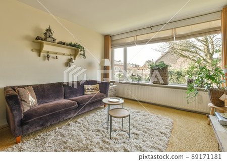 The interior of a spacious living room with a panoramic window and lots of house plants The interior of a spacious living room with a panoramic window and lots of house plants 89171181
