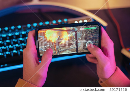 Hands of gamer playing mobile video games on his smartphone Hands of gamer playing mobile video games on his smartphone 89171536