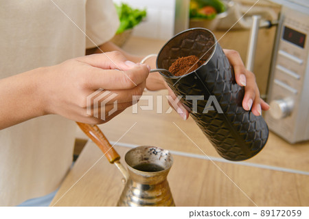 Closeup view of hands making ground coffee at home in turkish cezve 89172059