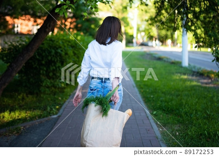 Beautiful girl with a paper bag with groceries. 89172253