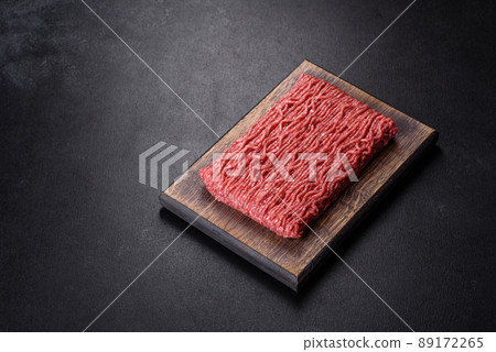 Fresh raw mince with spices and herbs on a dark concrete background Fresh raw mince with spices and herbs on a dark concrete background 89172265