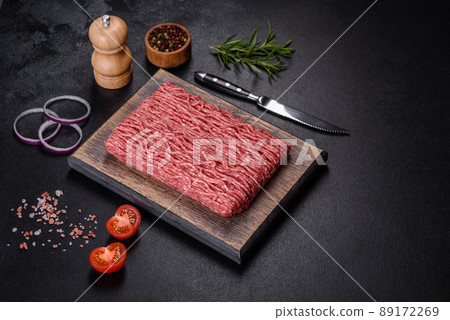 Fresh raw mince with spices and herbs on a dark concrete background Fresh raw mince with spices and herbs on a dark concrete background 89172269