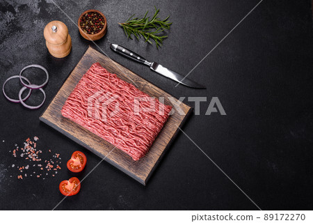 Fresh raw mince with spices and herbs on a dark concrete background Fresh raw mince with spices and herbs on a dark concrete background 89172270