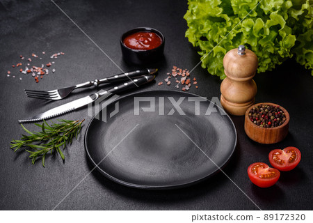 Empty round black plate on dark moody black background with copy space 89172320