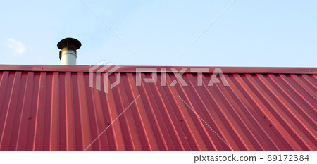 Tiled roof top with chimney with blue cloudy sky in background. Smoke raising from a chimney Tiled roof top with chimney with blue cloudy sky in background. Smoke raising from a chimney 89172384