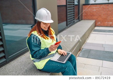 Hard working woman construction engineer standing on a construction site. Confident engineer talking on the phone and show casing work in progress  89172419