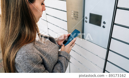 Post locker. Delivery automat terminal and hands with parcel courier box. Parcel delivery, pickup point with lockers, hand with parcel, contactless pack delivery. 89173162