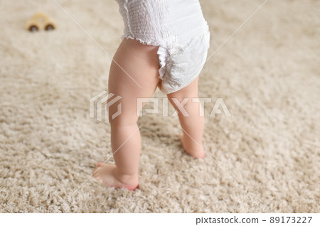 close-up - a baby in a disposable diaper on the background of a fluffy carpet. 89173227