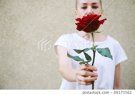 Faceless portrait of woman holding red rose in hand. Close-Up Of female Hands Holding Rose. Hipster woman hand holding a red rose 89173562
