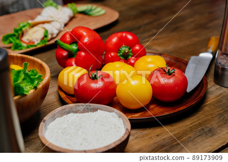 a wooden utensil with flour and vegetables on the kitchen table. 89173909