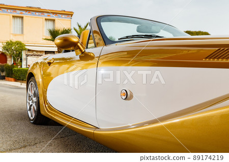 Close up view of exclusive vintage car is standing on narrow small streets, replica on the famous convertible car in French Riviera, Cap Ferrat, retro type, gold color, roadster, cote dazur Close up view of exclusive vintage car is standing on narrow small streets, replica on the famous convertible car in French Riviera, Cap Ferrat, retro type, gold color, roadster, cote dazur 89174219