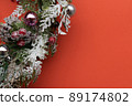 Orange background with christmas wreath, decorated with balls and pine cones 89174802