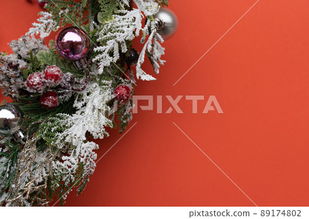 Orange background with christmas wreath, decorated with balls and pine cones Orange background with christmas wreath, decorated with balls and pine cones 89174802