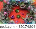 Orange background with christmas wreath, decorated with balls and pine cones 89174804