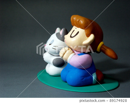 A girl and a cat who close their eyes and put their hands together to make a wish 89174928