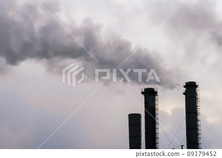 Environmental pollution - factory smokestack emitting smoke against grey sky 89179452