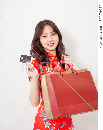Portrait of a young asian woman wearing traditional cheongsam qipao dress holding shopping bags and showing credit card isolated on wihte background. Portrait of a young asian woman wearing traditional cheongsam qipao dress holding shopping bags and showing credit card isolated on wihte background. 89179651