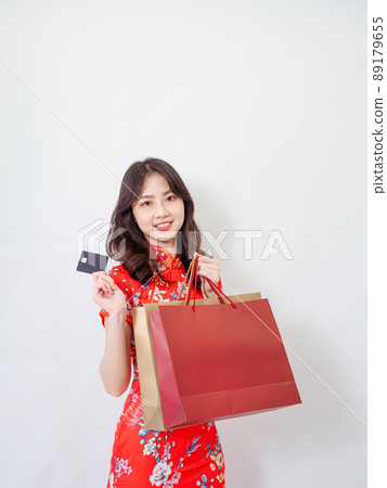 Portrait of a young asian woman wearing traditional cheongsam qipao dress holding shopping bags and showing credit card isolated on wihte background. Portrait of a young asian woman wearing traditional cheongsam qipao dress holding shopping bags and showing credit card isolated on wihte background. 89179655