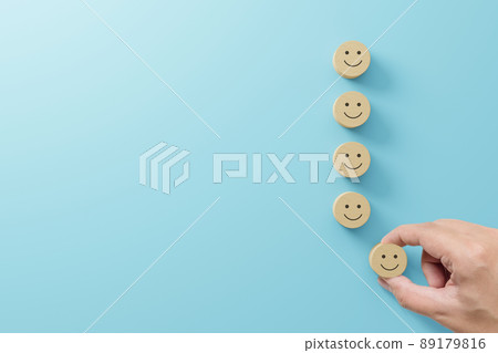 Hand choose wooden cube block with icon face smile on light blue background Hand choose wooden cube block with icon face smile on light blue background 89179816