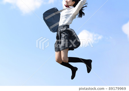 A smiling female student jumping under the blue sky A smiling female student jumping under the blue sky 89179969