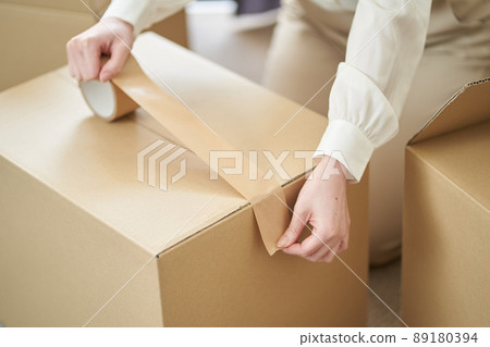 Asian woman sticking gum tape on cardboard 89180394