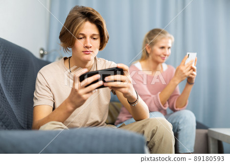 Modern teenager engrossed in mobile online phone game at home 89180593