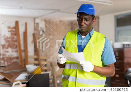 Responsible contractor standing with papers in building during renovations Responsible contractor standing with papers in building during renovations 89180715
