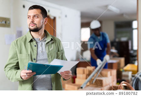 Architect making notes on indoor construction site Architect making notes on indoor construction site 89180782