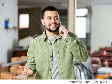 Owner of building under construction inspects the room being renovated and talks on mobile phone Owner of building under construction inspects the room being renovated and talks on mobile phone 89180812