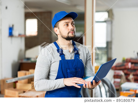 Builder handyman checking plan of house renovation on laptop 89180879