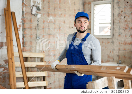 Professional builder holds wooden bars in his hands 89180880