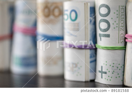 On the table there are Polish banknotes rolled up in a row and tied with a rubber band. On the table there are Polish banknotes rolled up in a row and tied with a rubber band. 89181588